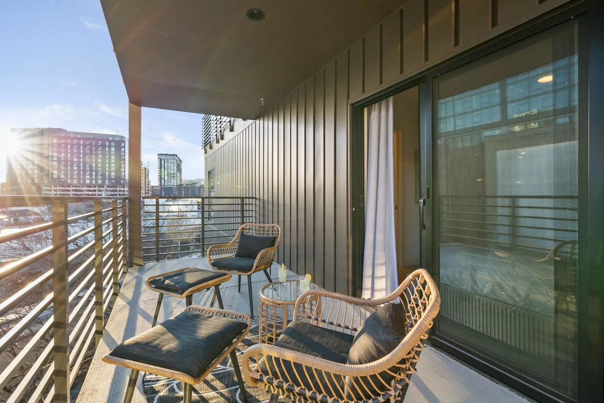 An outdoor balcony seating area with a glass table and city views, inviting relaxation and al fresco dining. The peaceful mood and urban outlook reflect the enjoyment of private evenings overlooking Nashville.