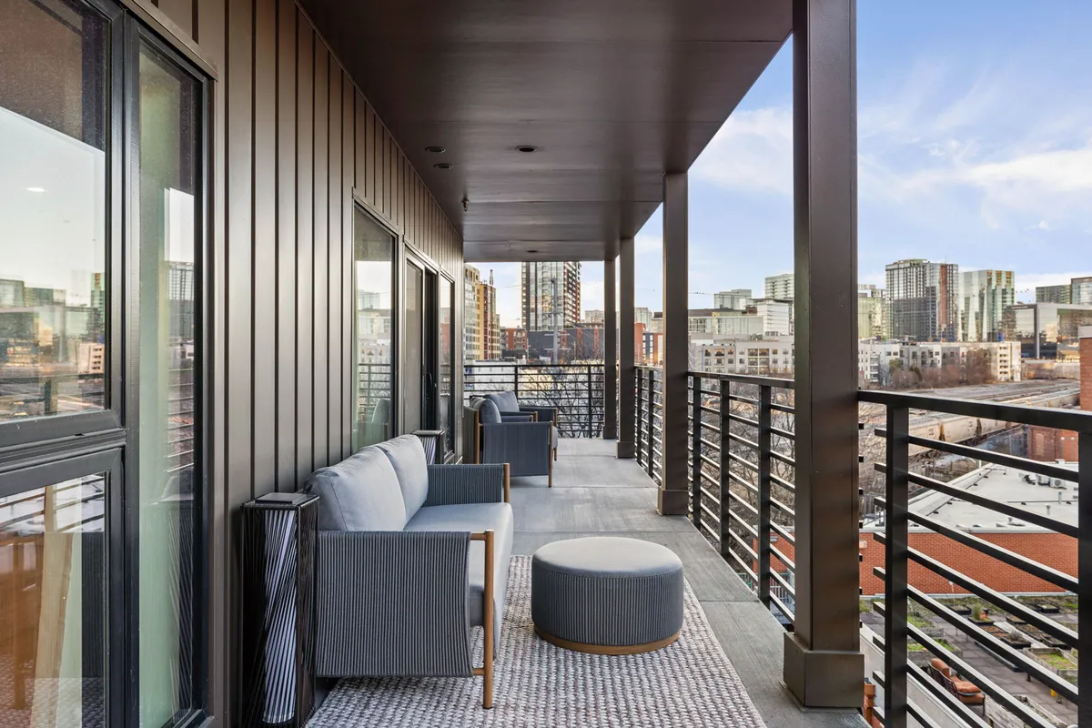 A sophisticated exterior view from an outdoor seating area with a clear sightline to the vibrant city skyline. The scene is set for relaxing moments, with comfortable seating and a tranquil urban backdrop, perfect for enjoying romantic sunsets or quiet reflection.