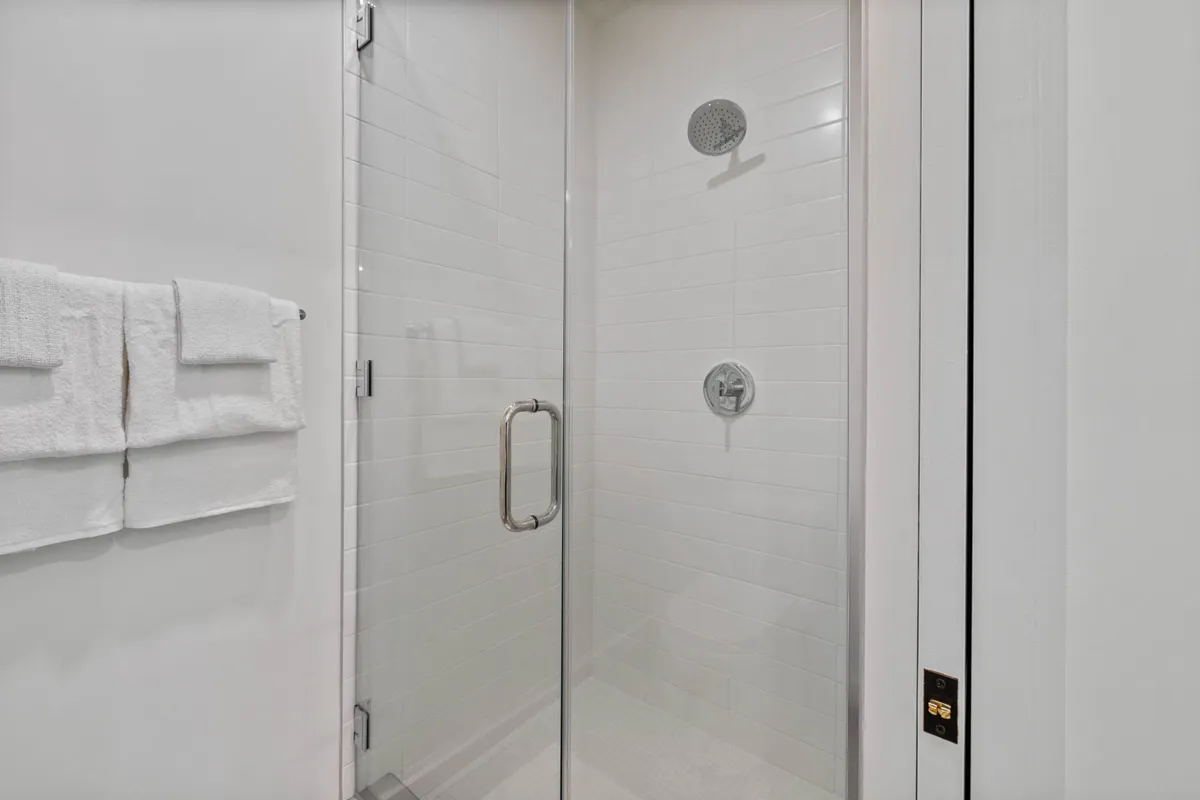 A modern bathroom with a glass shower enclosure, sleek fixtures, and crisp white towels. The space exudes tranquility and is designed for comfort and relaxation after a long day.